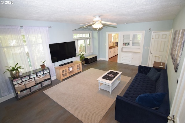 living area with baseboards, a ceiling fan, a textured ceiling, and wood finished floors