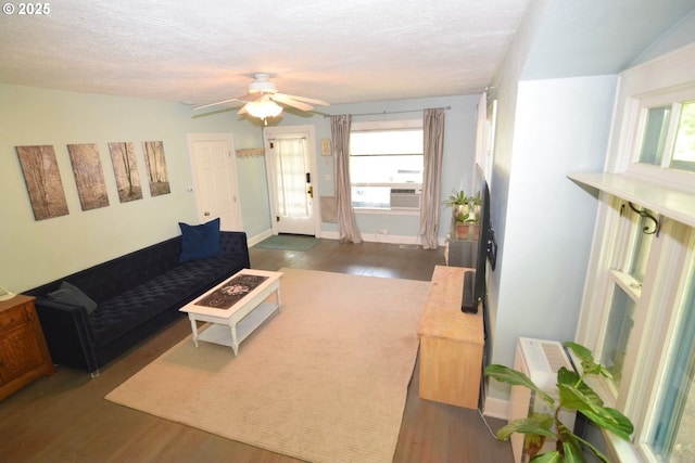 living area featuring dark wood-style flooring, ceiling fan, plenty of natural light, and baseboards