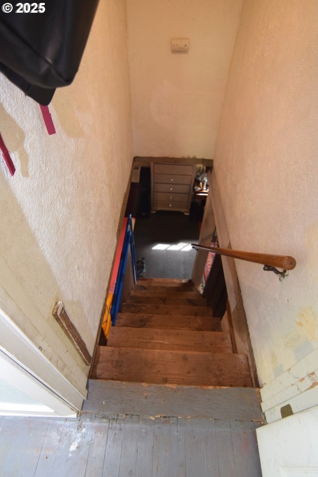 staircase featuring a textured wall and hardwood / wood-style flooring