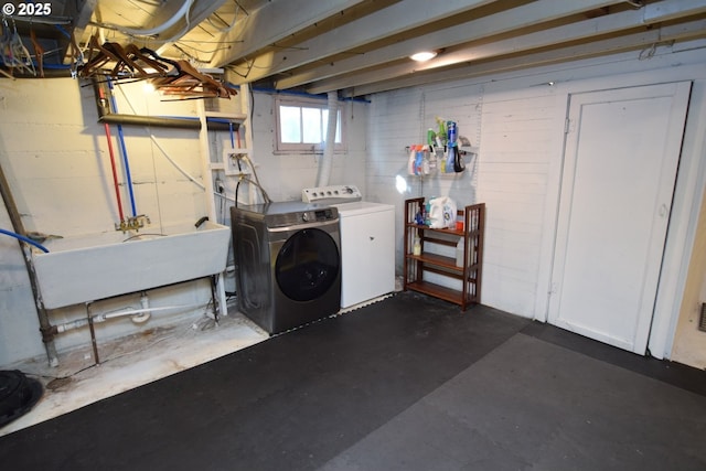 washroom featuring a sink, concrete block wall, laundry area, and washing machine and clothes dryer
