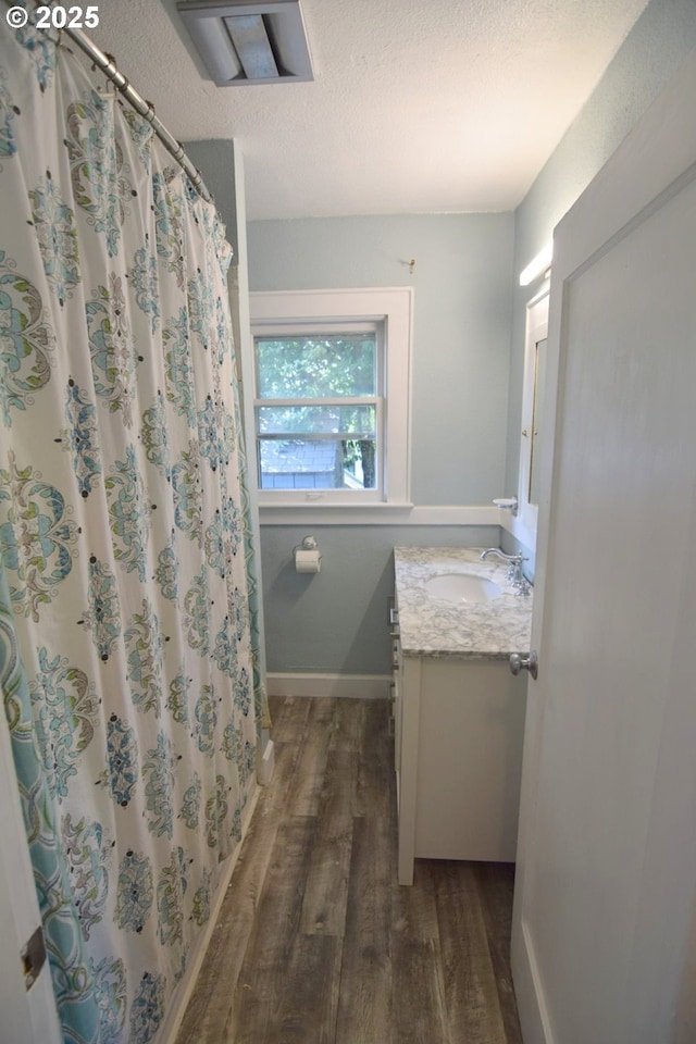 bathroom featuring a shower with curtain, a textured ceiling, wood finished floors, vanity, and baseboards