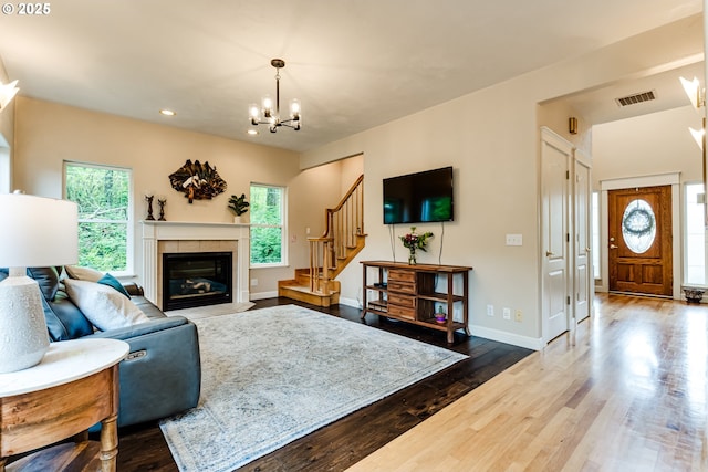 living room with an inviting chandelier, wood-type flooring, and a tile fireplace