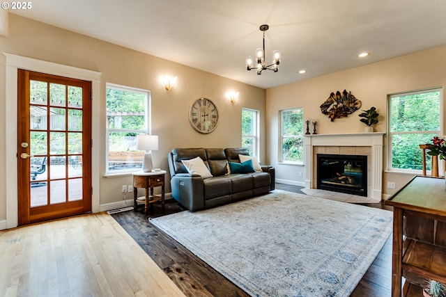 living room featuring a tiled fireplace, wood-type flooring, and a notable chandelier