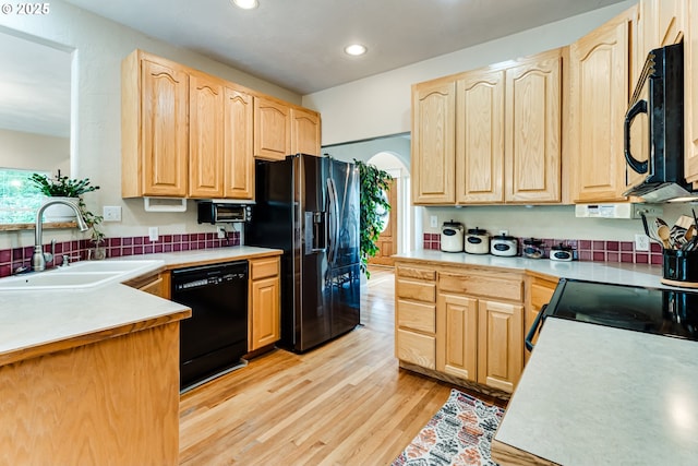 kitchen featuring light brown cabinetry, sink, light wood-type flooring, kitchen peninsula, and black appliances