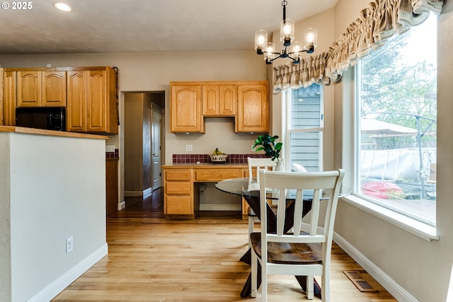 kitchen with decorative light fixtures, light wood-type flooring, and a notable chandelier