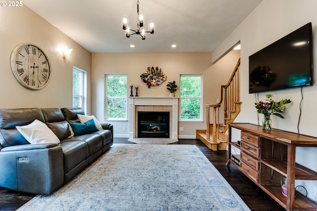 living room featuring a tile fireplace, dark wood-type flooring, and a notable chandelier