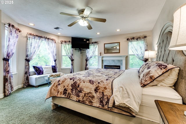 bedroom with carpet floors, a tile fireplace, and ceiling fan