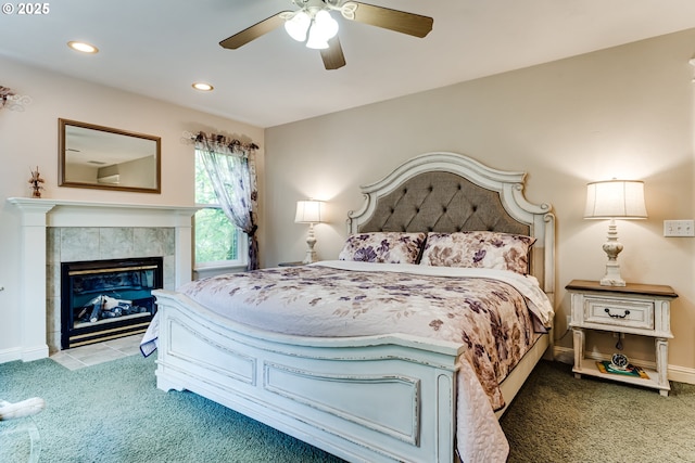 carpeted bedroom with a tile fireplace and ceiling fan