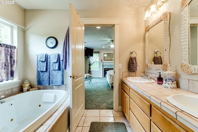 bathroom with tile patterned flooring, vanity, a relaxing tiled tub, and a healthy amount of sunlight