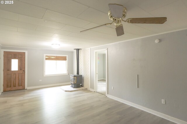 58798 Fairview Rd, Coquille, OR 97423 - unfurnished living room with a wood stove, a ceiling fan, wood finished floors, and baseboards
