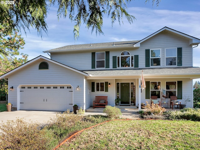 traditional-style house with a garage, concrete driveway, a porch, and a front yard