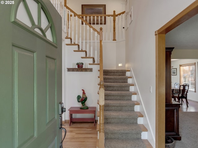 staircase with a towering ceiling, baseboards, and wood finished floors