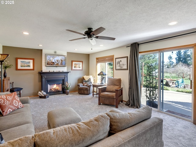 carpeted living room featuring recessed lighting, ceiling fan, a textured ceiling, and a glass covered fireplace