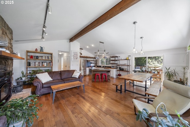 49867 Hills Creek Rd, Oakridge, OR 97463 - living area featuring lofted ceiling with beams, track lighting, a stone fireplace, and hardwood / wood-style flooring