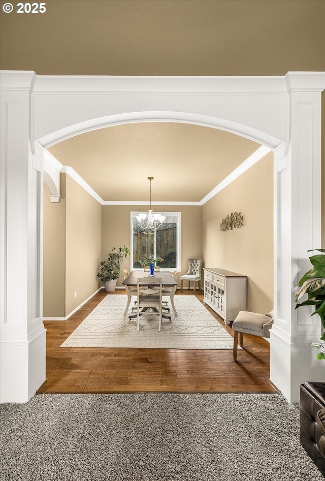 dining area featuring an inviting chandelier, arched walkways, wood finished floors, and ornamental molding