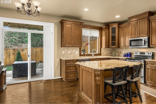 kitchen with light stone counters, stainless steel appliances, dark wood-type flooring, backsplash, and glass insert cabinets