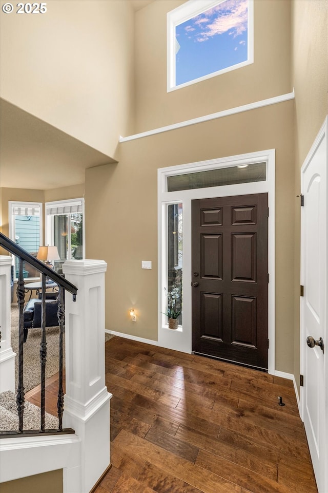 foyer entrance with stairs, a healthy amount of sunlight, a towering ceiling, and hardwood / wood-style flooring