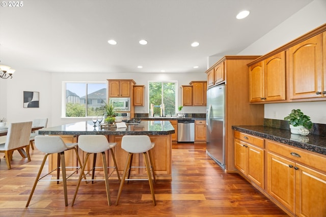 12988 NW Tigon Ln, Portland, OR 97229 - kitchen featuring appliances with stainless steel finishes, a breakfast bar area, a kitchen island, recessed lighting, and dark wood-type flooring
