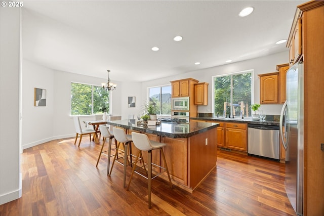 12988 NW Tigon Ln, Portland, OR 97229 - kitchen featuring appliances with stainless steel finishes, plenty of natural light, a kitchen island, brown cabinetry, and recessed lighting
