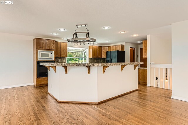 15911 NE 29th Ave, Ridgefield, WA 98642 - kitchen featuring black appliances, a kitchen breakfast bar, light wood-style flooring, recessed lighting, and brown cabinetry