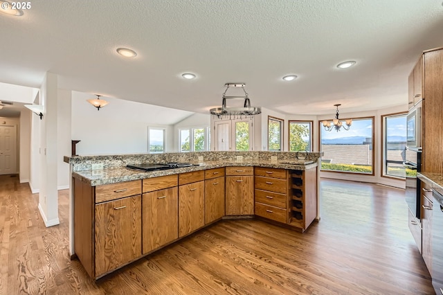 15911 NE 29th Ave, Ridgefield, WA 98642 - kitchen with wood finished floors, a chandelier, brown cabinets, a textured ceiling, and light stone counters