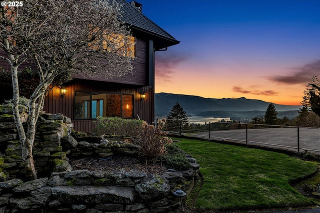 property exterior at dusk featuring a mountain view and a lawn