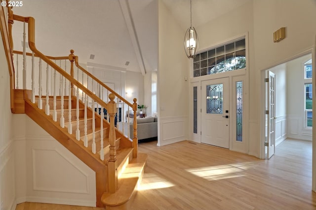 entryway with a high ceiling, an inviting chandelier, and light wood-type flooring