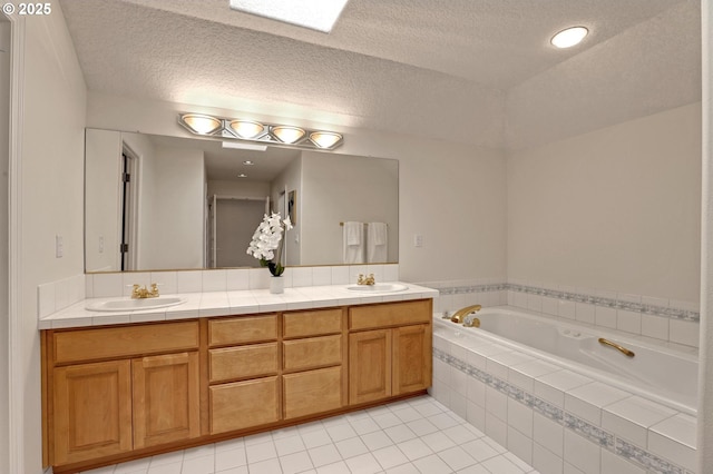 bathroom featuring a textured ceiling, tile patterned floors, tiled bath, and vanity