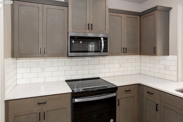 kitchen with stainless steel microwave, light countertops, electric range, and decorative backsplash