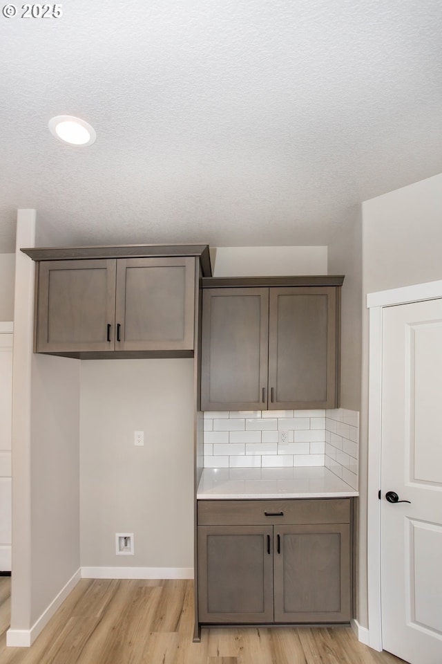 kitchen with baseboards, light wood-style flooring, light countertops, and decorative backsplash