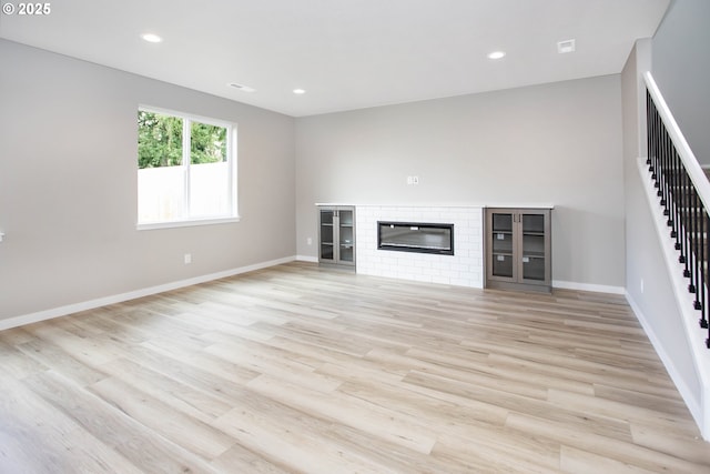 unfurnished living room with stairway, baseboards, light wood-style floors, and recessed lighting