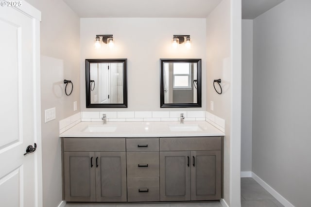 bathroom featuring baseboards, a sink, and double vanity