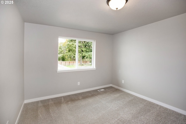 carpeted spare room with visible vents, baseboards, and a textured ceiling