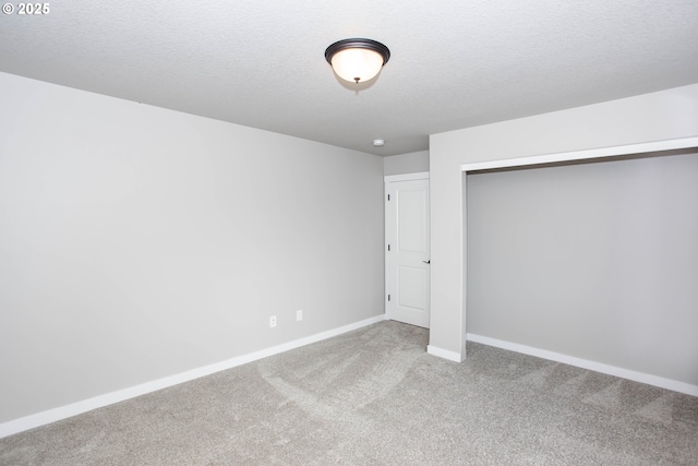 unfurnished bedroom featuring a textured ceiling, a closet, carpet flooring, and baseboards