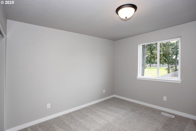 spare room featuring baseboards, visible vents, carpet, and a textured ceiling