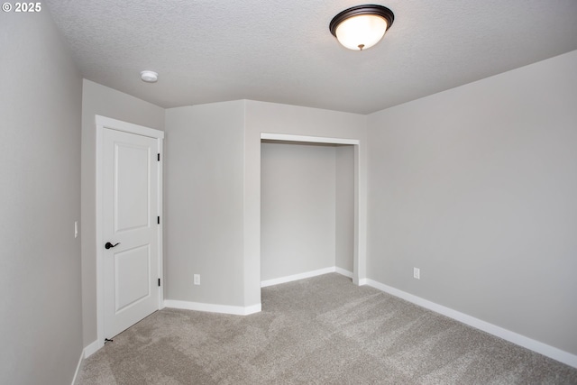 unfurnished bedroom with a closet, carpet, a textured ceiling, and baseboards