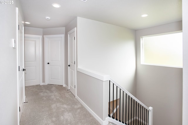 hall with recessed lighting, carpet, and an upstairs landing
