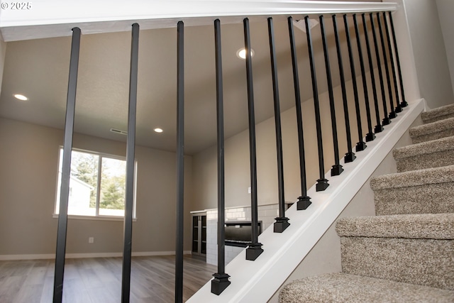 stairway featuring baseboards, wood finished floors, and recessed lighting