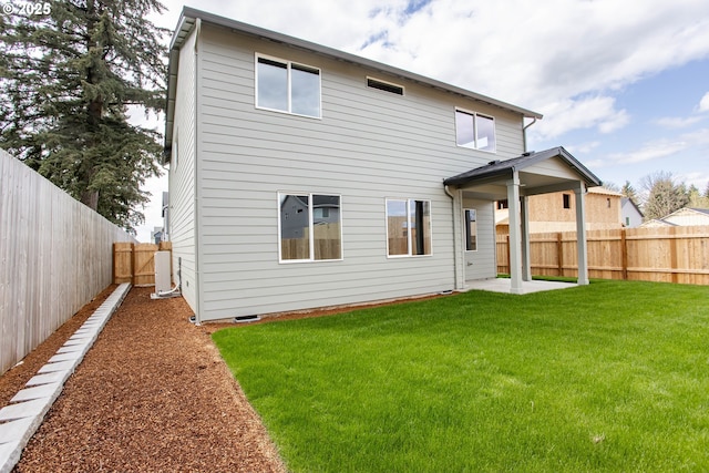 back of house with a fenced backyard, a patio area, and a lawn
