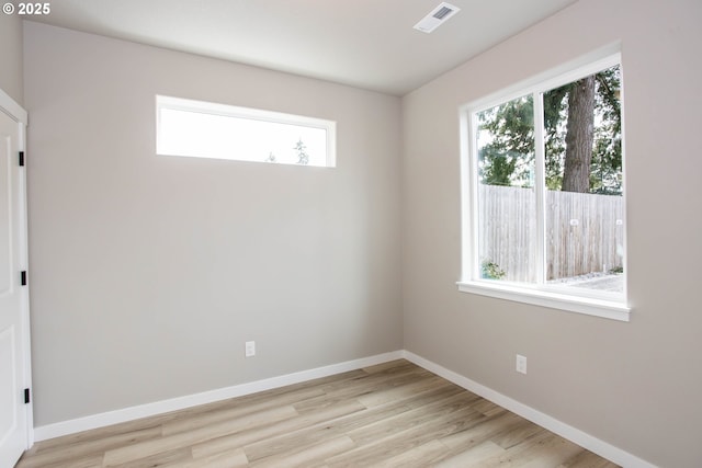 empty room featuring light wood-style floors, visible vents, and a healthy amount of sunlight