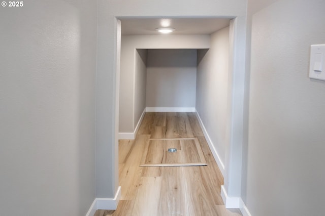 hallway featuring baseboards and wood finished floors