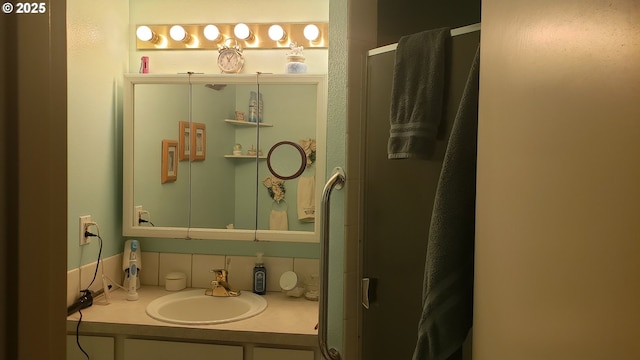 bathroom with a shower with door, vanity, and tasteful backsplash