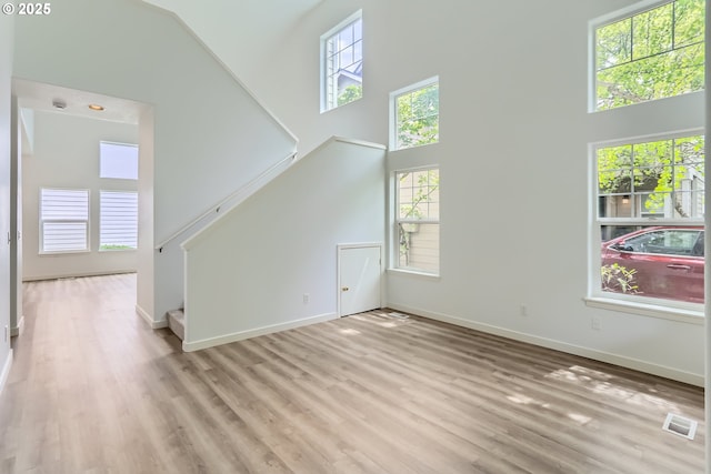 2370 NE 12th Way, Hillsboro, OR 97124 - unfurnished living room with a towering ceiling, stairs, light wood-style floors, and baseboards