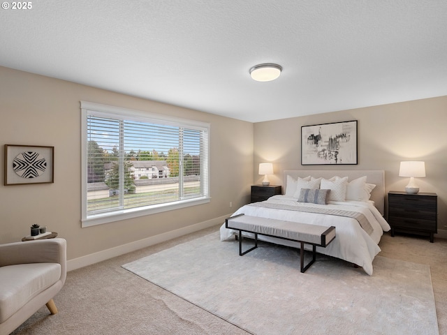 bedroom featuring baseboards, light colored carpet, and a textured ceiling