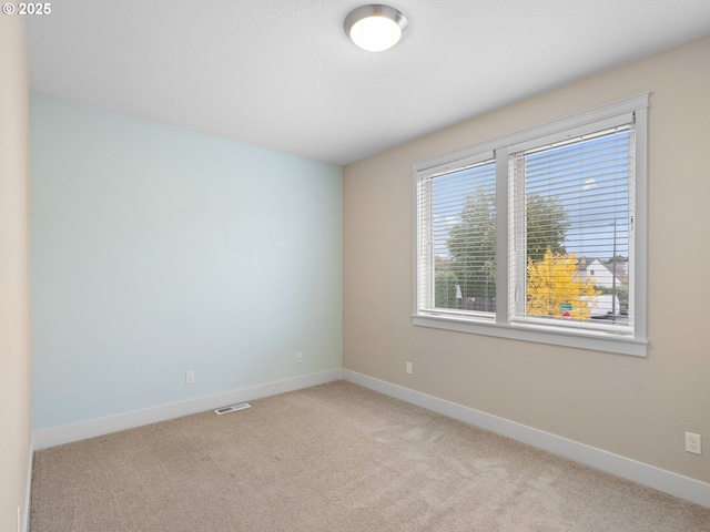 unfurnished room featuring light carpet, visible vents, and baseboards