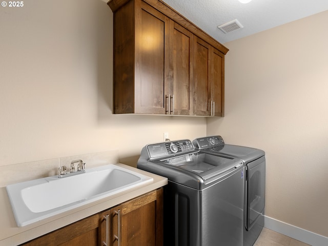 laundry room with visible vents, a sink, cabinet space, baseboards, and washing machine and clothes dryer