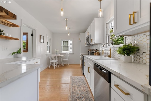 4004 N Montana Ave, Portland, OR 97227 - kitchen with stainless steel appliances, light wood-style floors, white cabinets, decorative backsplash, and decorative light fixtures