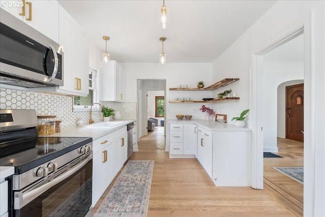 4004 N Montana Ave, Portland, OR 97227 - kitchen featuring appliances with stainless steel finishes, open shelves, arched walkways, light countertops, and decorative backsplash