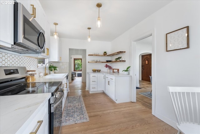 4004 N Montana Ave, Portland, OR 97227 - kitchen featuring appliances with stainless steel finishes, arched walkways, open shelves, white cabinets, and light wood-type flooring