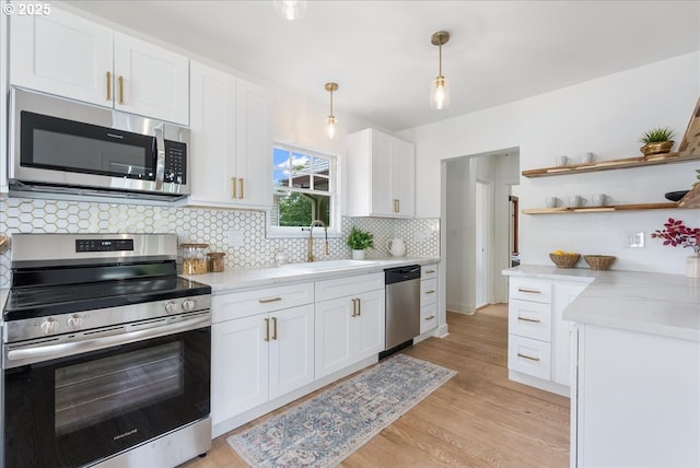 4004 N Montana Ave, Portland, OR 97227 - kitchen featuring appliances with stainless steel finishes, white cabinets, open shelves, decorative backsplash, and light wood-style floors